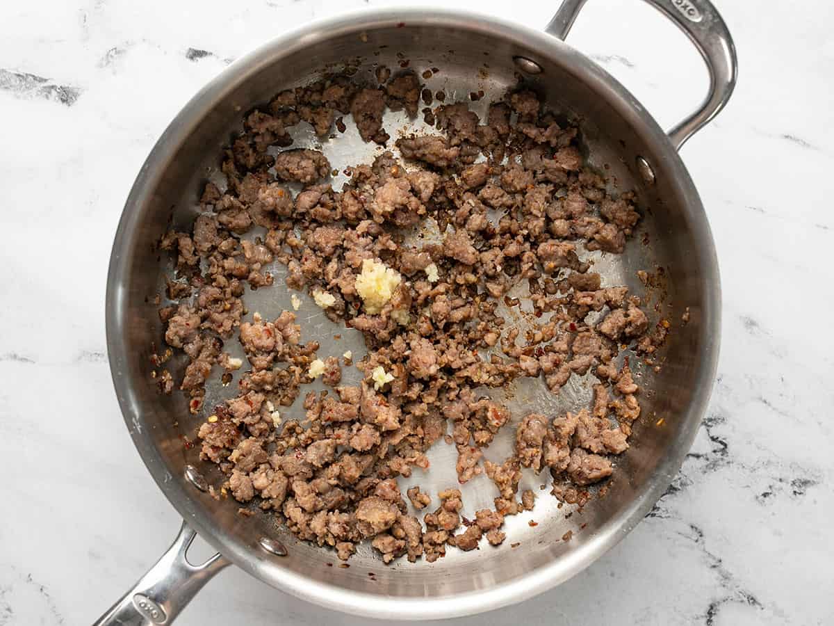 Browned Italian sausage in the skillet with minced garlic.