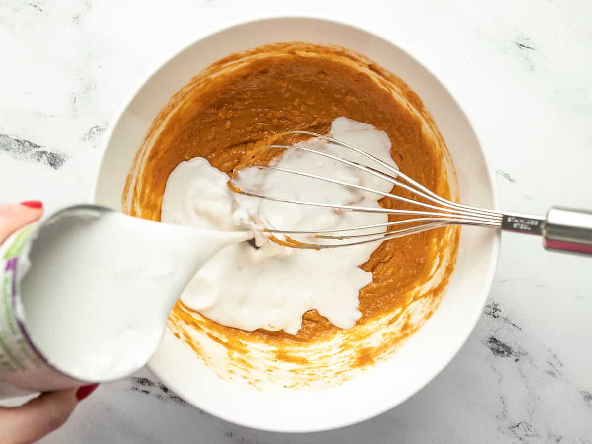 Coconut milk being poured into the peanut sauce.