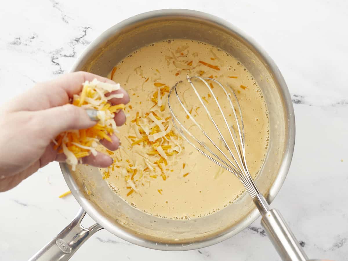 Cheese being added to the sauce in the sauce pot.