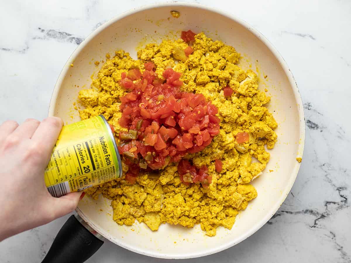 Diced tomatoes with green chiles being poured into the skillet.