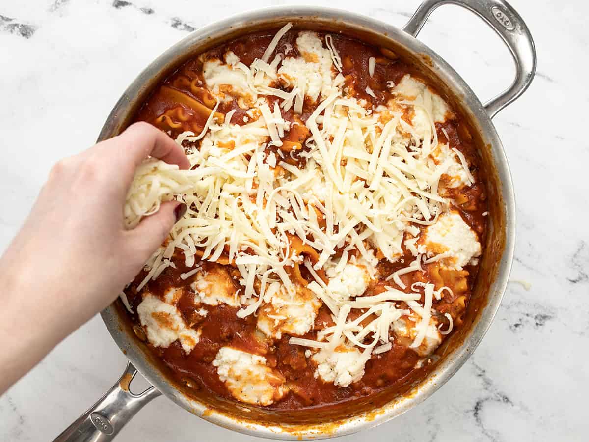 Cheese being added to the skillet lasagna.