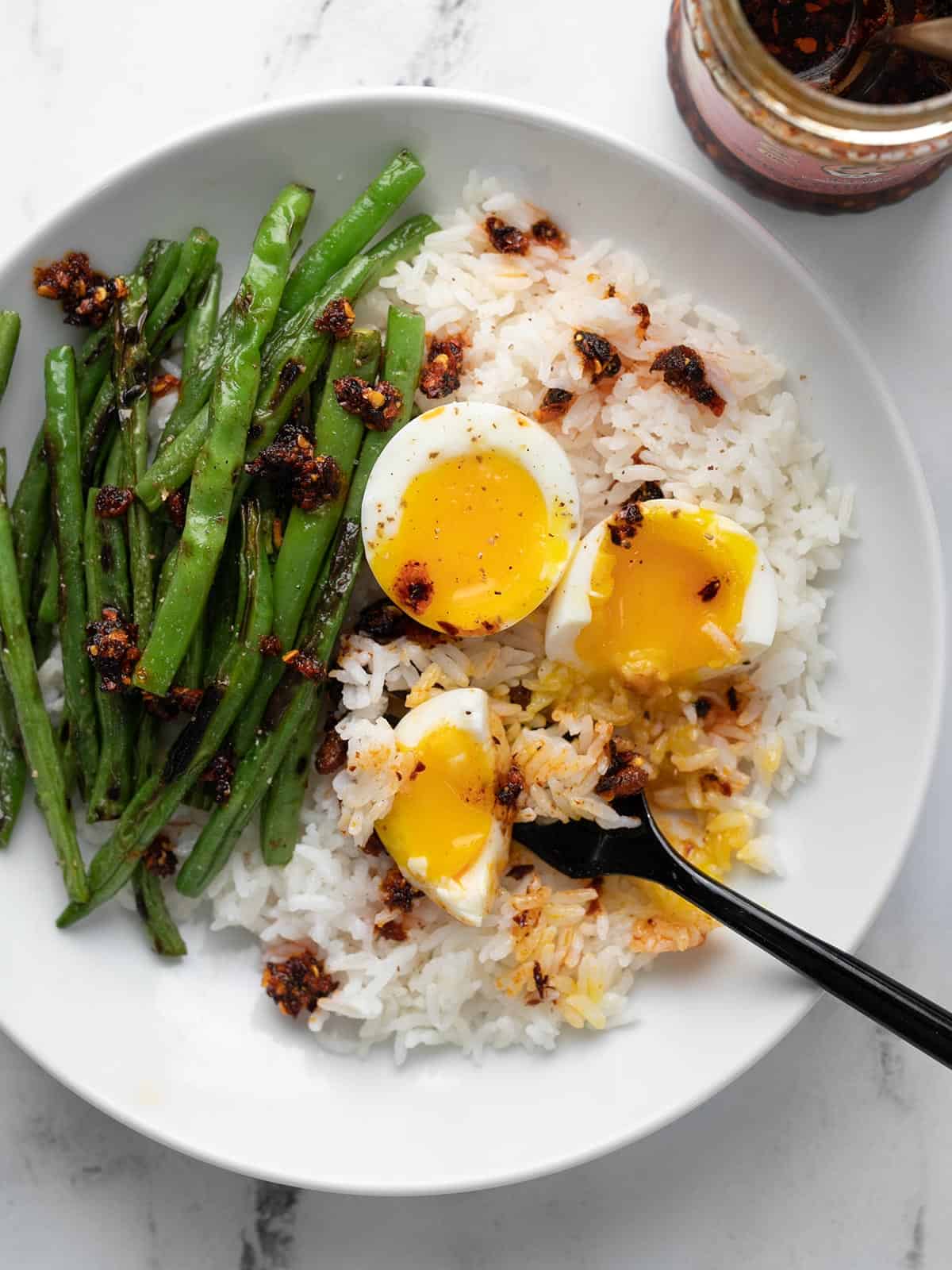 Blistered green bean rice bowl with a black fork in it.