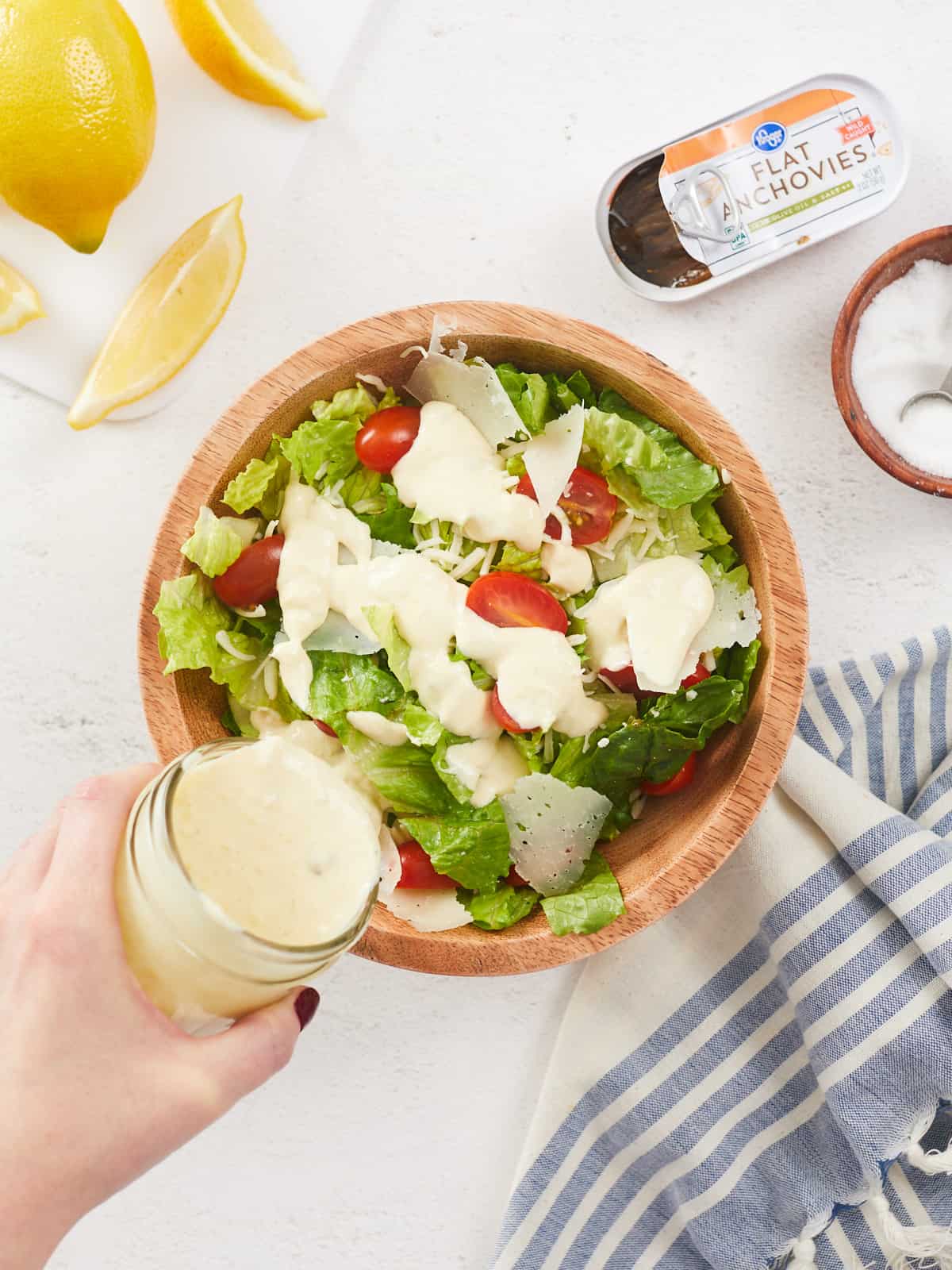 Overhead view of Caesar dressing being poured over a salad.