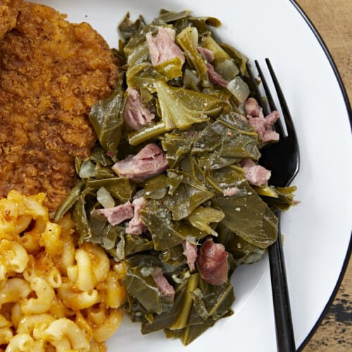 Overhead view of collard greens on a plate with chicken and mac and cheese.