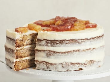 Side shot of Hummingbird Cake with a slice being taken out of it.