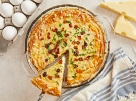 Overhead shot of a slice of Quiche Lorraine being lifted out of the pie plate.