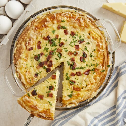 Overhead shot of a slice of Quiche Lorraine being lifted out of the pie plate.