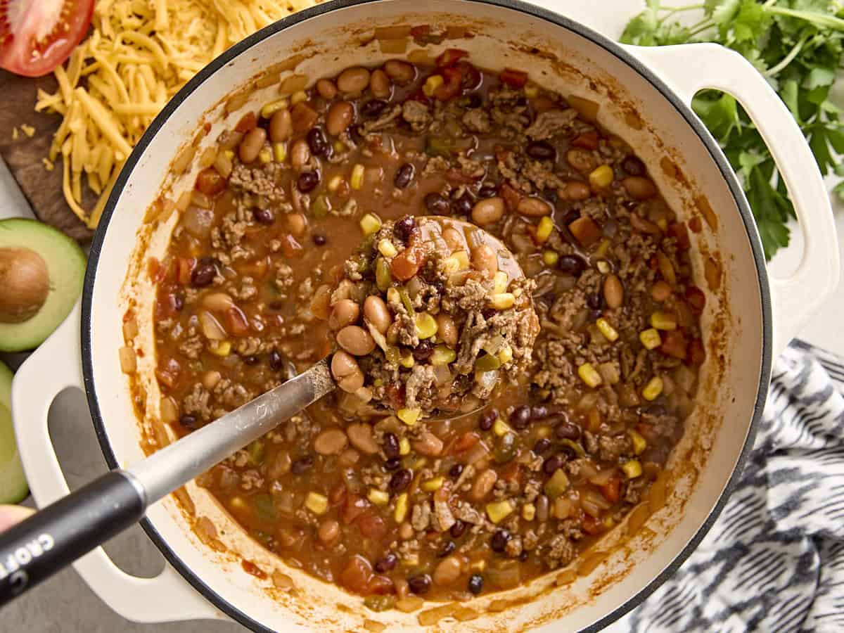 Overhead view of taco soup with a serving spoon taking some from the dutch oven.