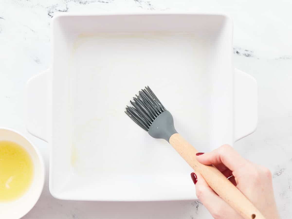 Prepping the baking dish with melted butter.