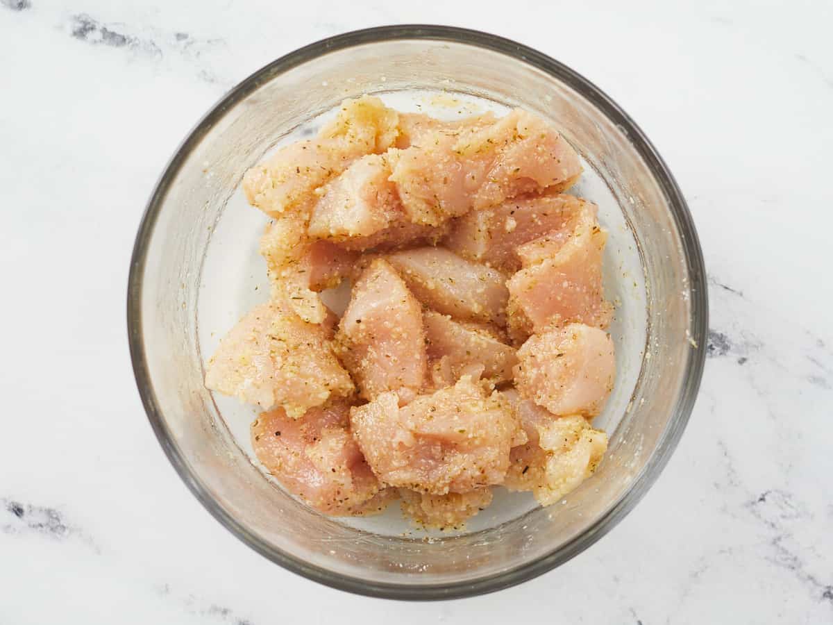 Raw seasoned chicken breast in a bowl.