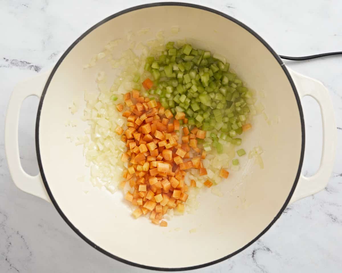 Overhead shot of celery, onion, and carrot in Dutch oven.