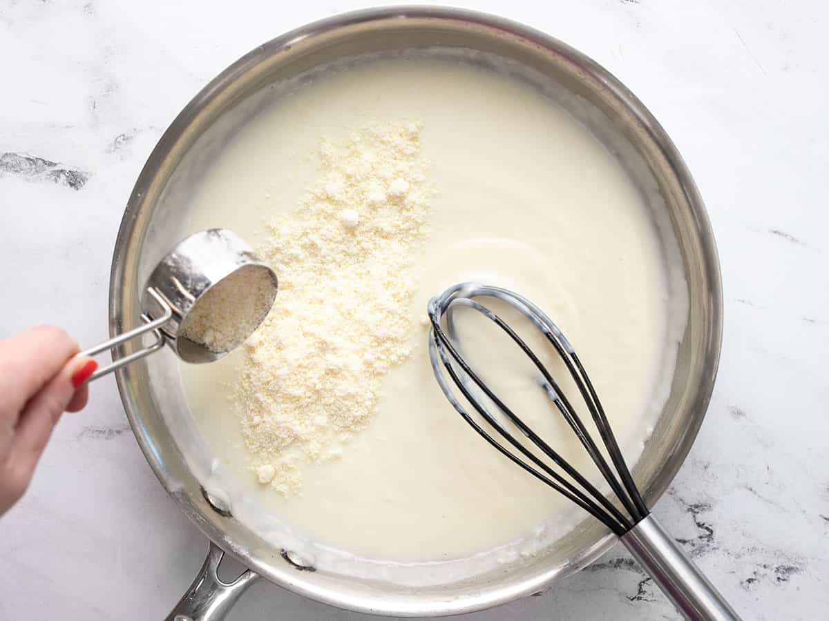 Grated Parmesan being sprinkled into the skillet.