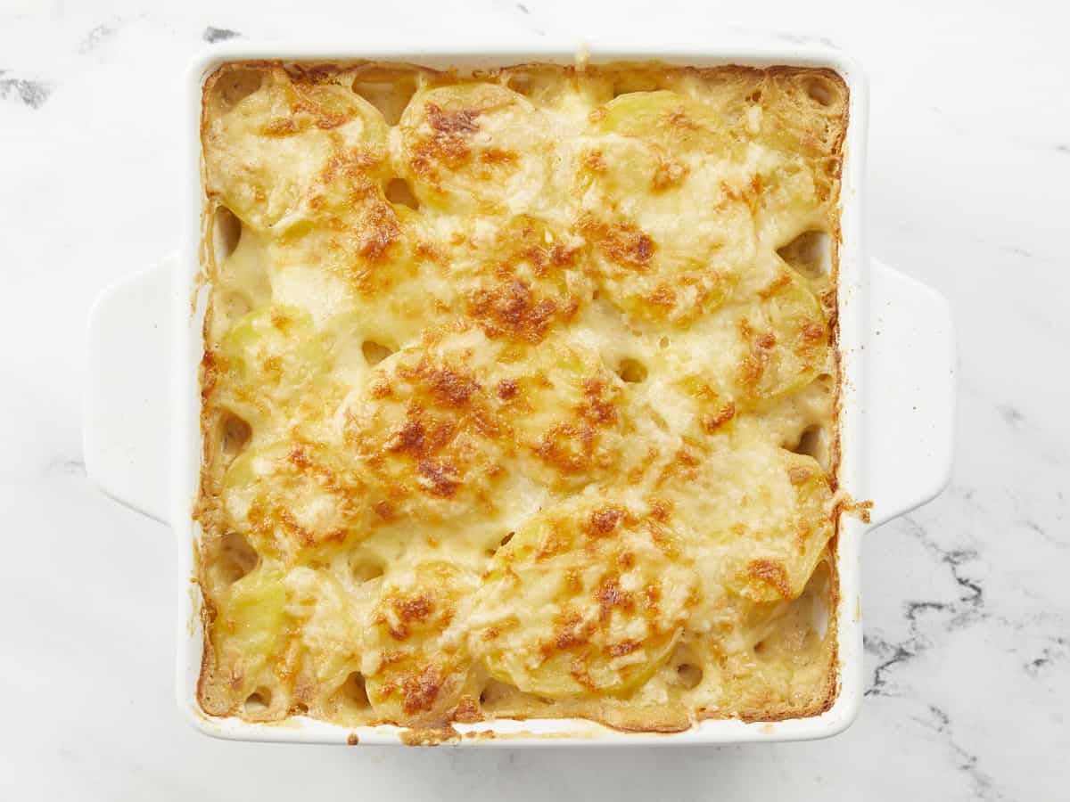 Overhead shot of scalloped potatoes in a white casserole dish.