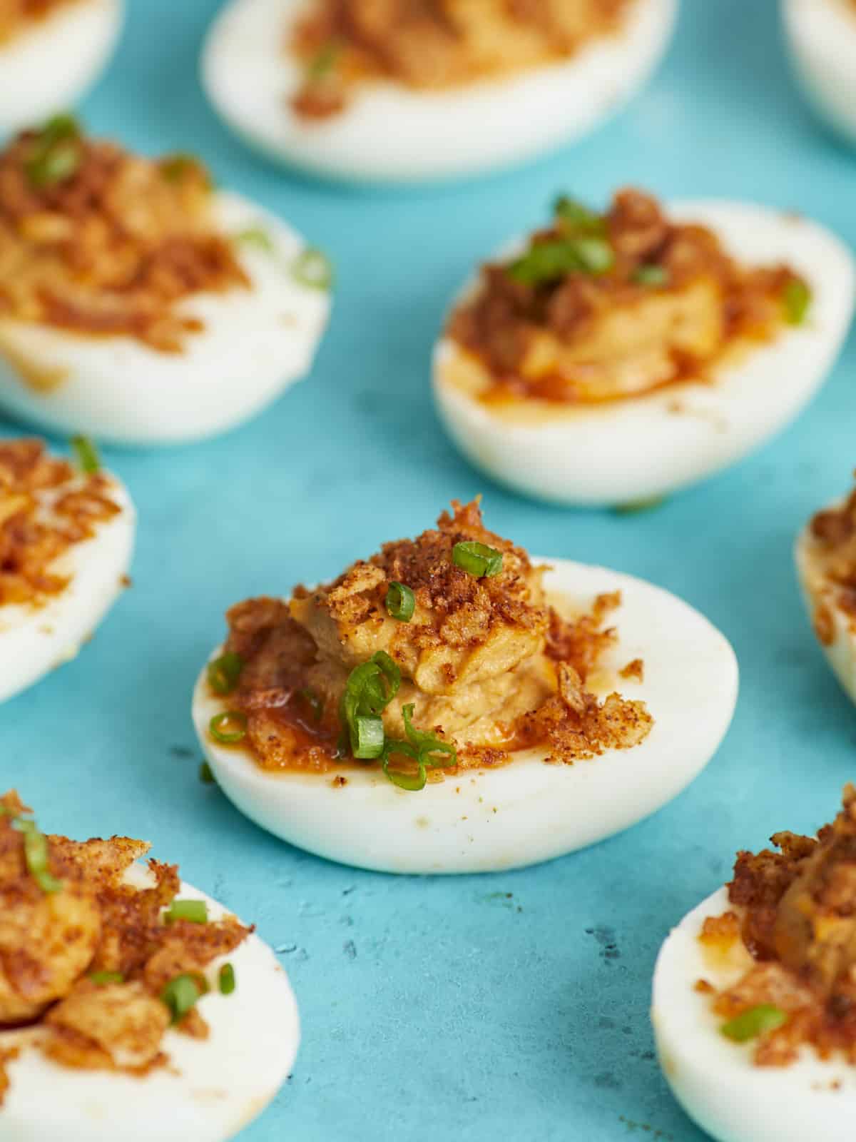 Side shot of Nashville Hot Deviled Eggs on aqua background.