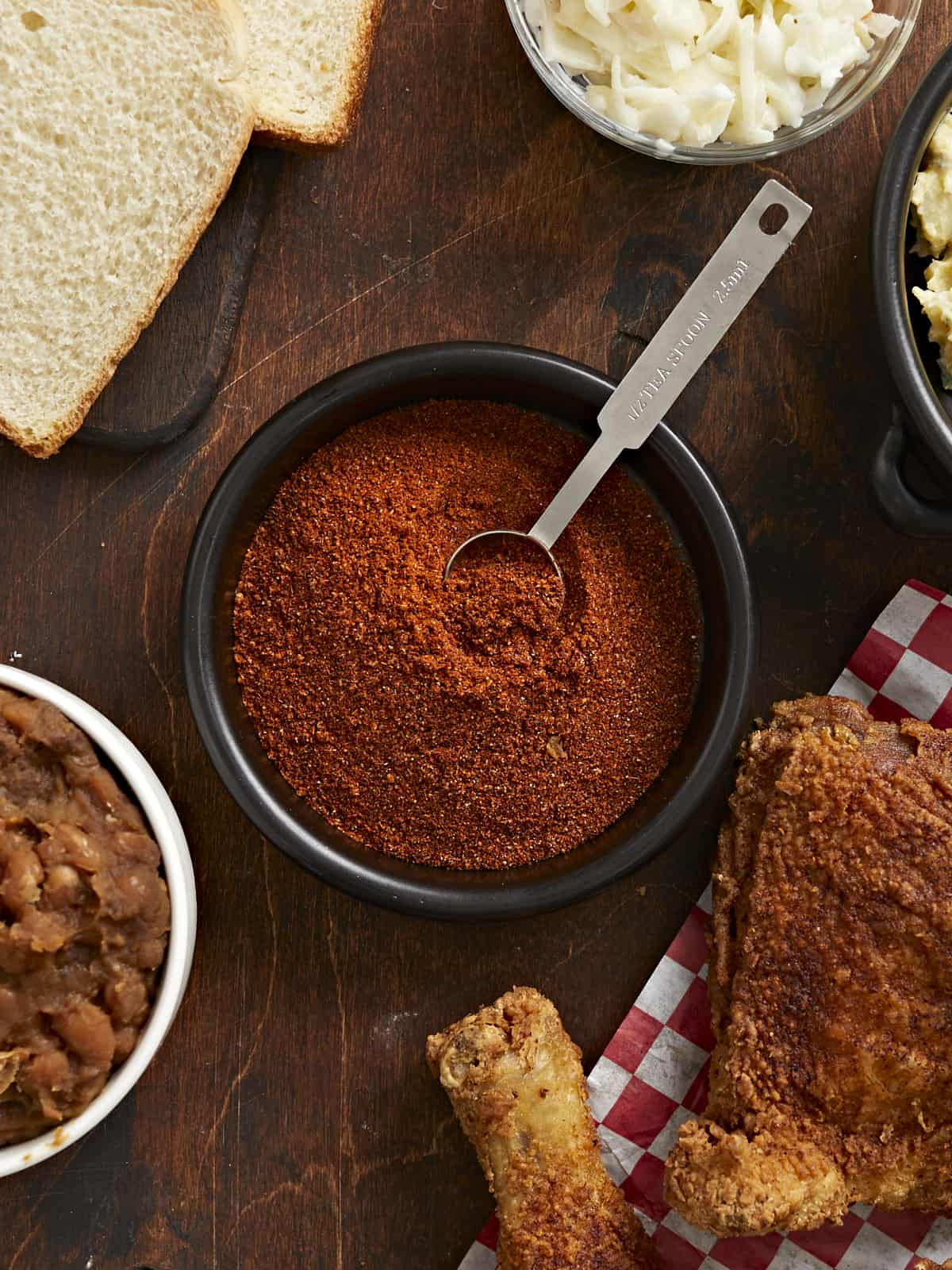 Overhead shot of Nashville Hot Seasoning in a black bowl with a silver measuring spoon in it.