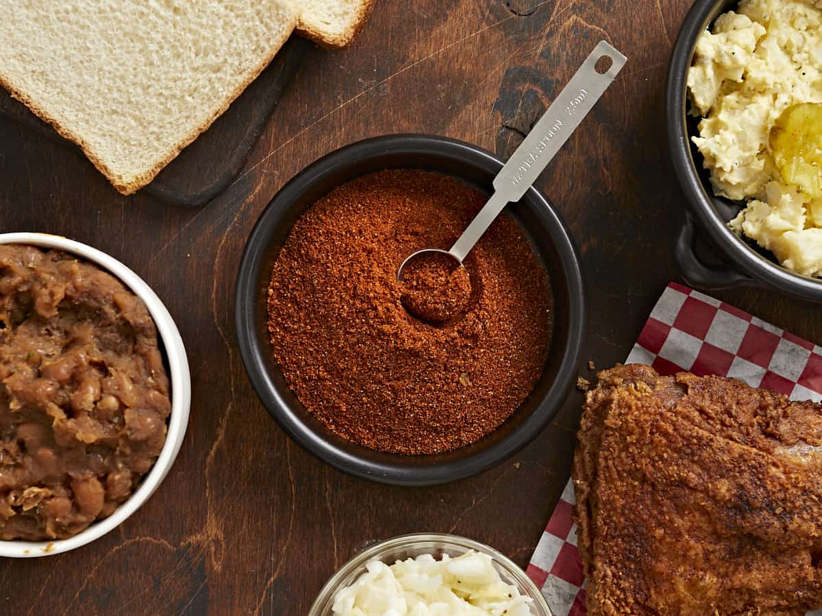 Overhead shot of Nashville Hot Seasoning in a black bowl with a silver measuring spoon in it.