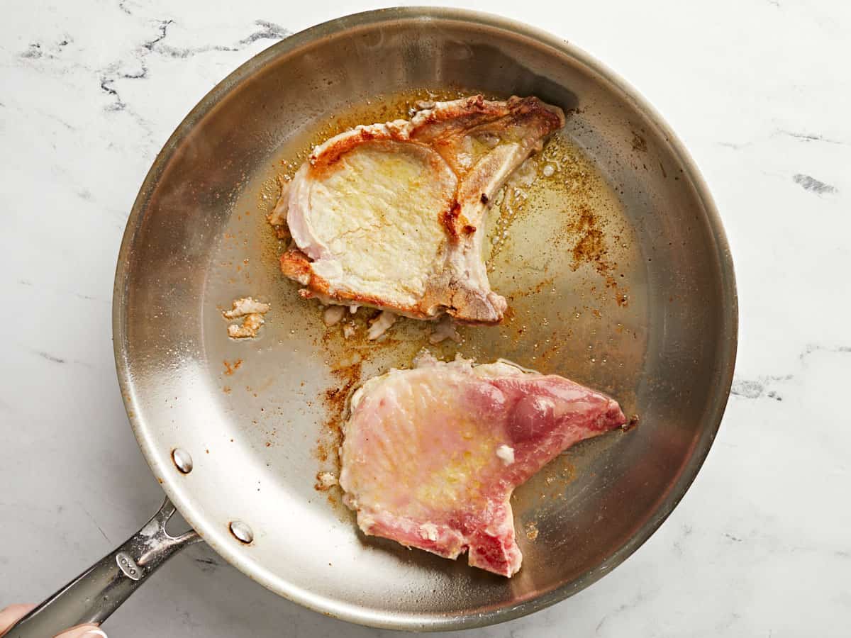 Pork Chops being browned in the skillet.