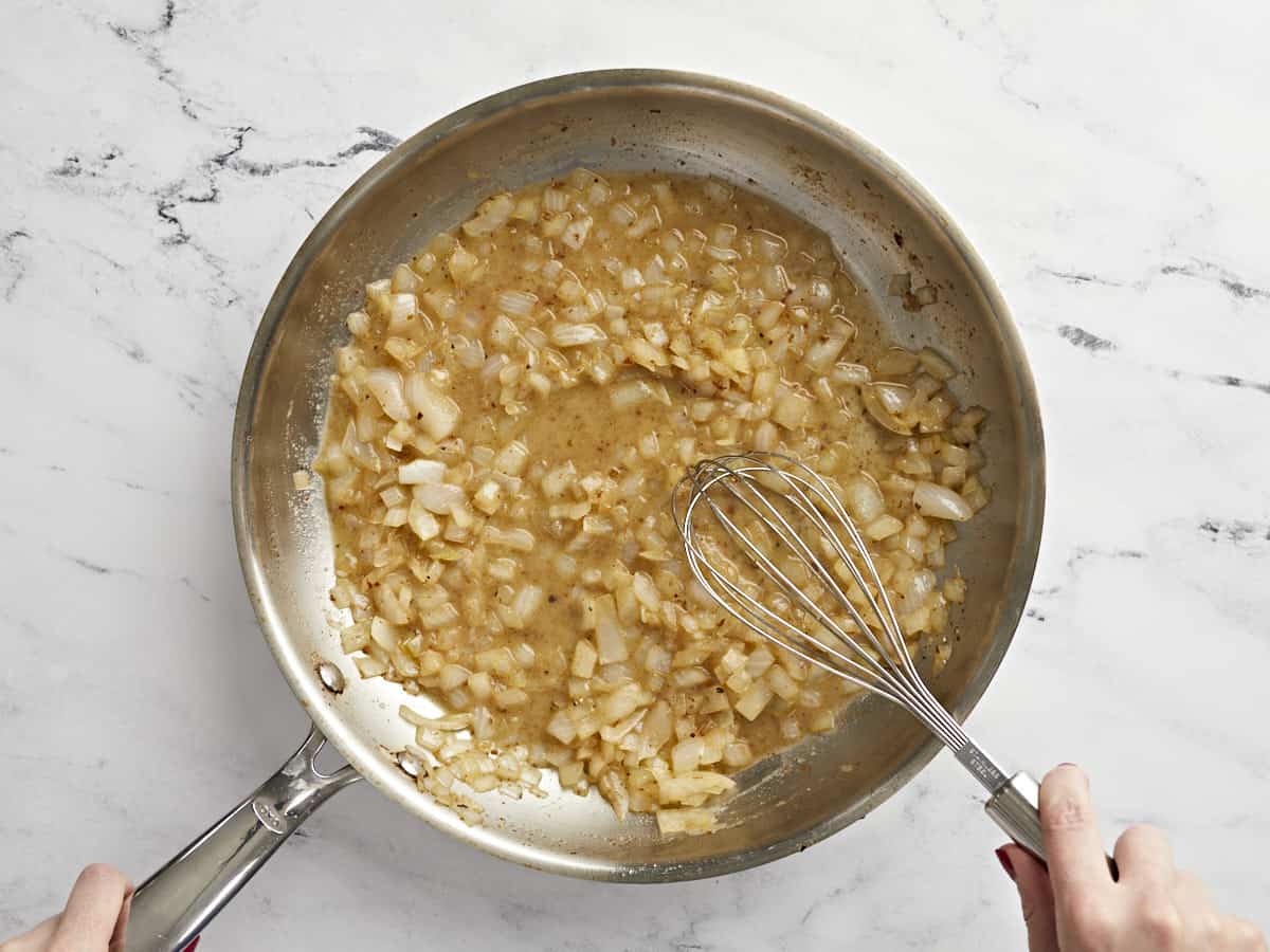 Onions and vinaigrette being whisked in the skillet.