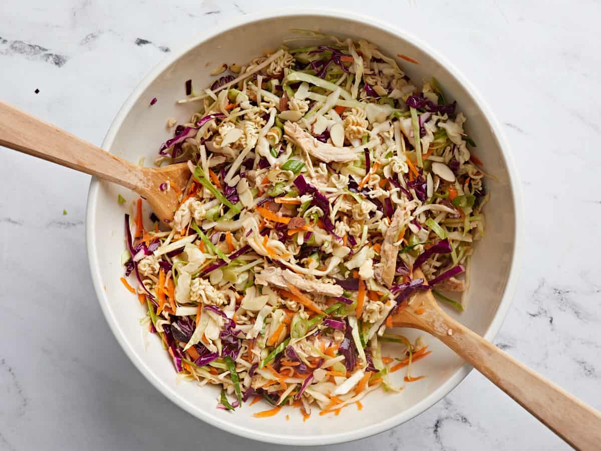 Finished ramen noodle salad in a bowl with wooden utensils.