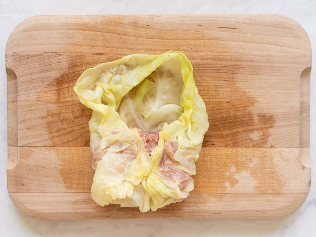 Overhead view of stuffed cabbage leaf with sides tucked and leaf rolled over stuffing.