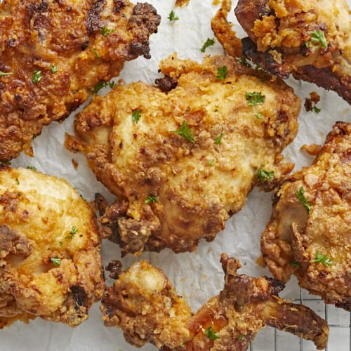 Overhead close up view of Air Fryer Fried Chicken on parchment paper and a cooling rack.