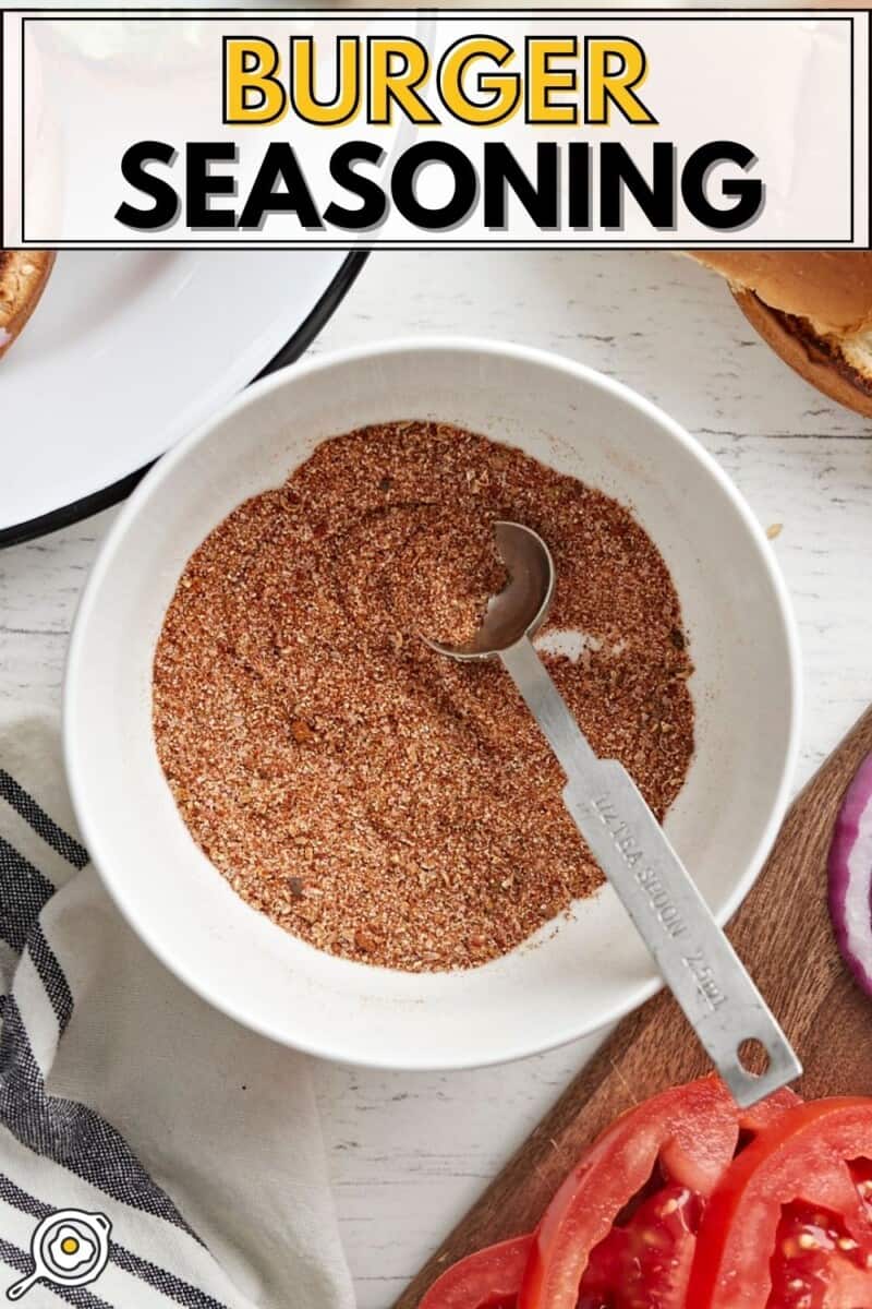 Overhead view of a bowl full of burger seasoning with a measuring spoon.