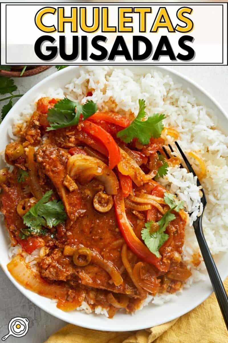 Overhead shot of Chuletas Guisadas over rice in a white bowl with a black fork in it.