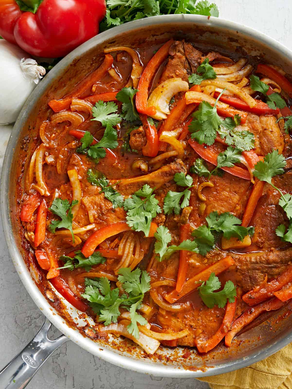 Close up overhead view of a pan full of Chuletas Guisadas.