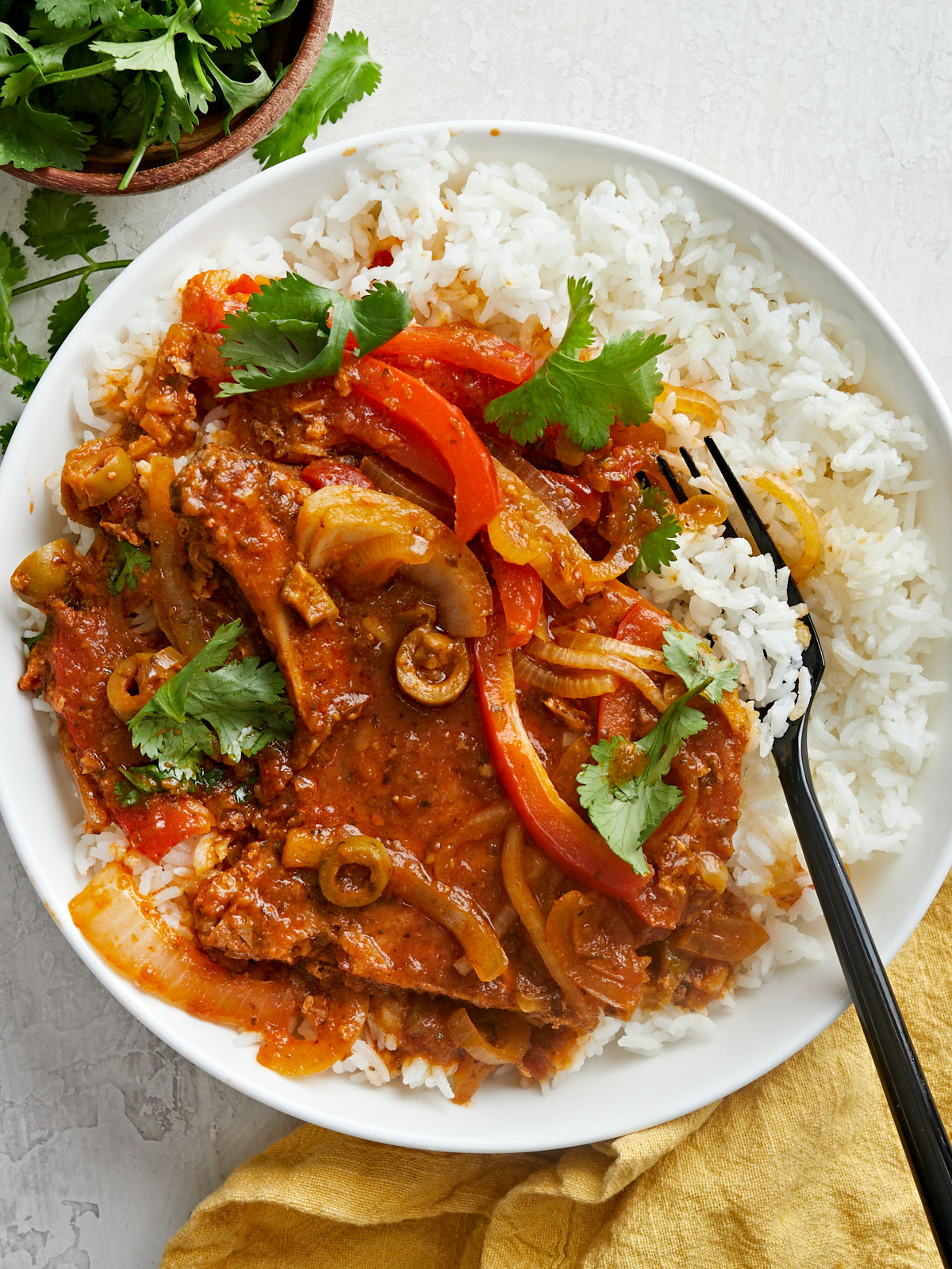 Close up overhead shot of Chuletas Guisadas on a plate with rice.