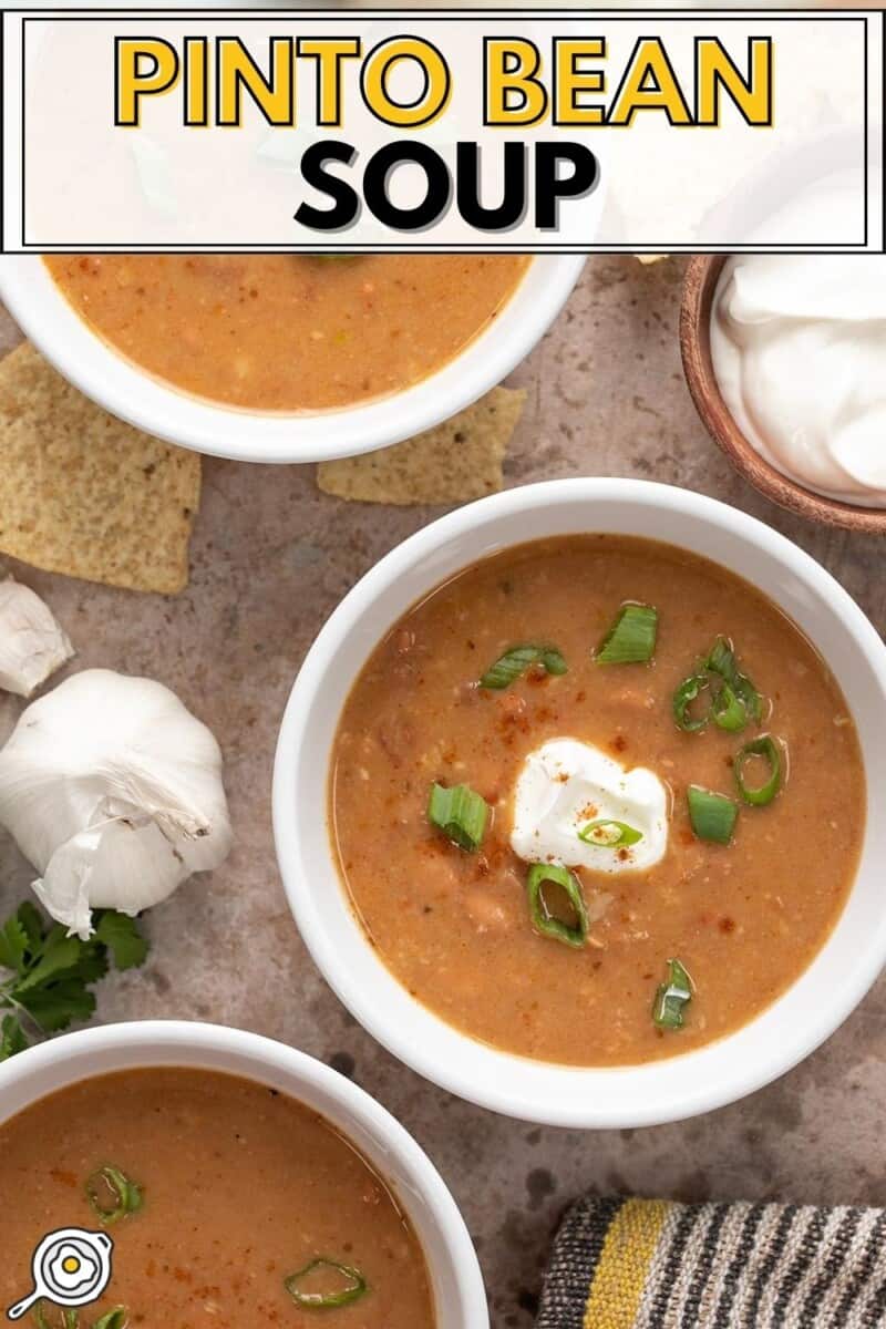 Overhead view of three bowls of pinto bean soup with sour cream and green onions.