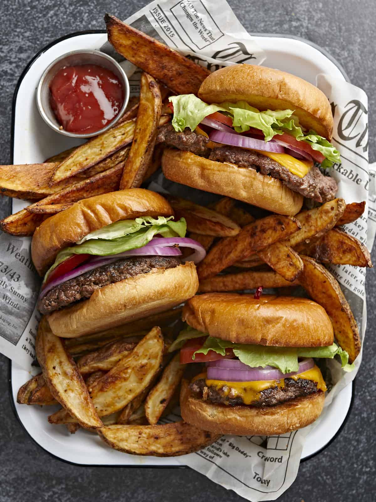 Overhead shot of three Smash Burgers tucked into a tray with fries nestled around them.