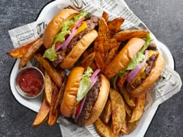 Overhead shot of three Smash Burgers tucked into a tray with fries nestled around them.