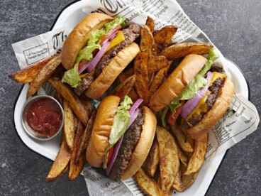 Overhead shot of three Smash Burgers tucked into a tray with fries nestled around them.