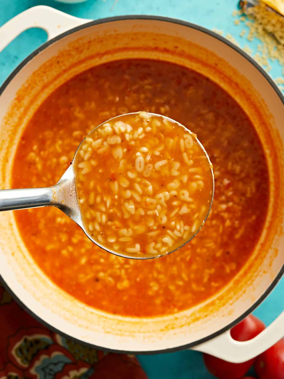 Close up of a ladle full of sopa de letras over the soup pot.