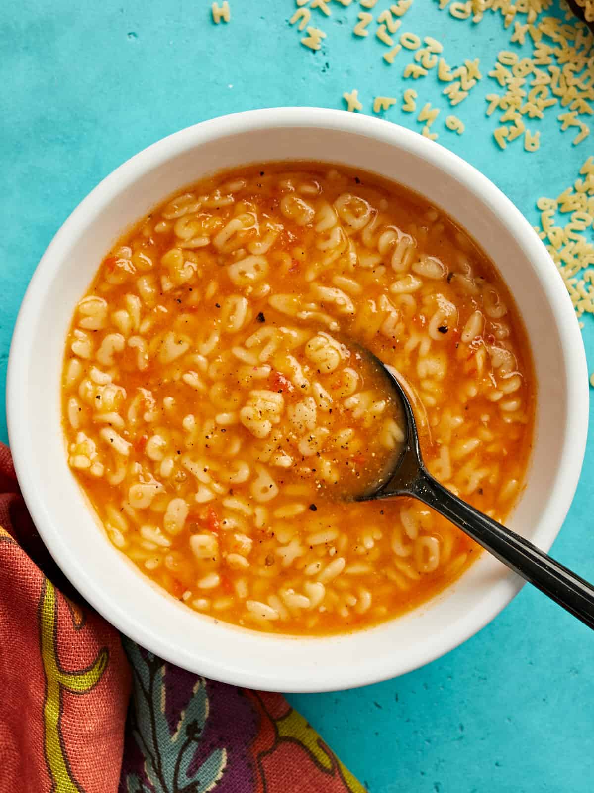 Overhead view of a bowl full of sopa de letras with a spoon in the center. 