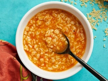 Overhead view of a bowl full of sopa de letras with a spoon in the center.