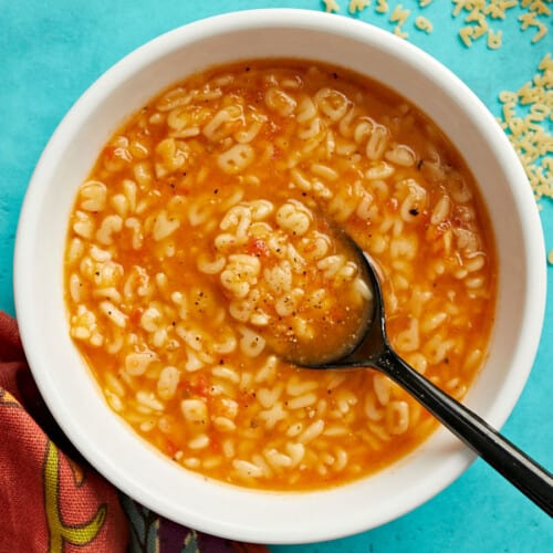 Overhead view of a bowl full of sopa de letras with a spoon in the center.