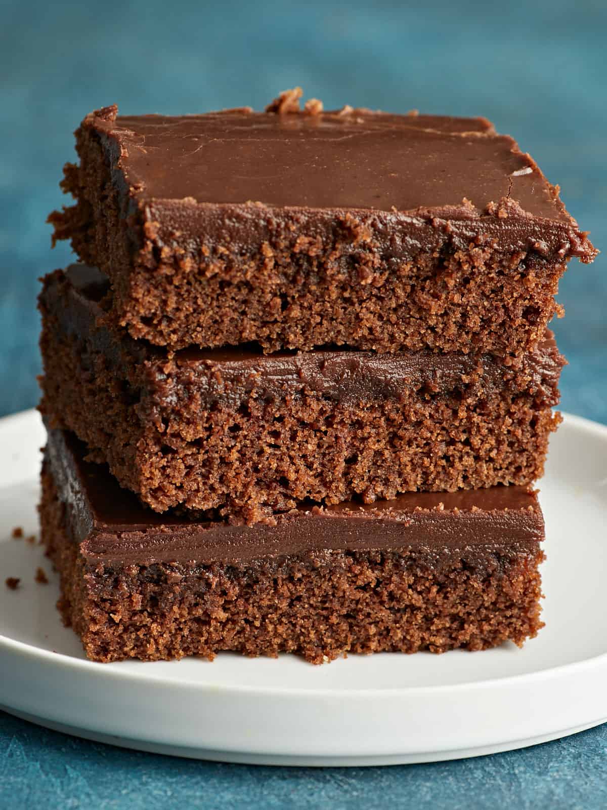 A stack of three slices of chocolate cake on a plate.