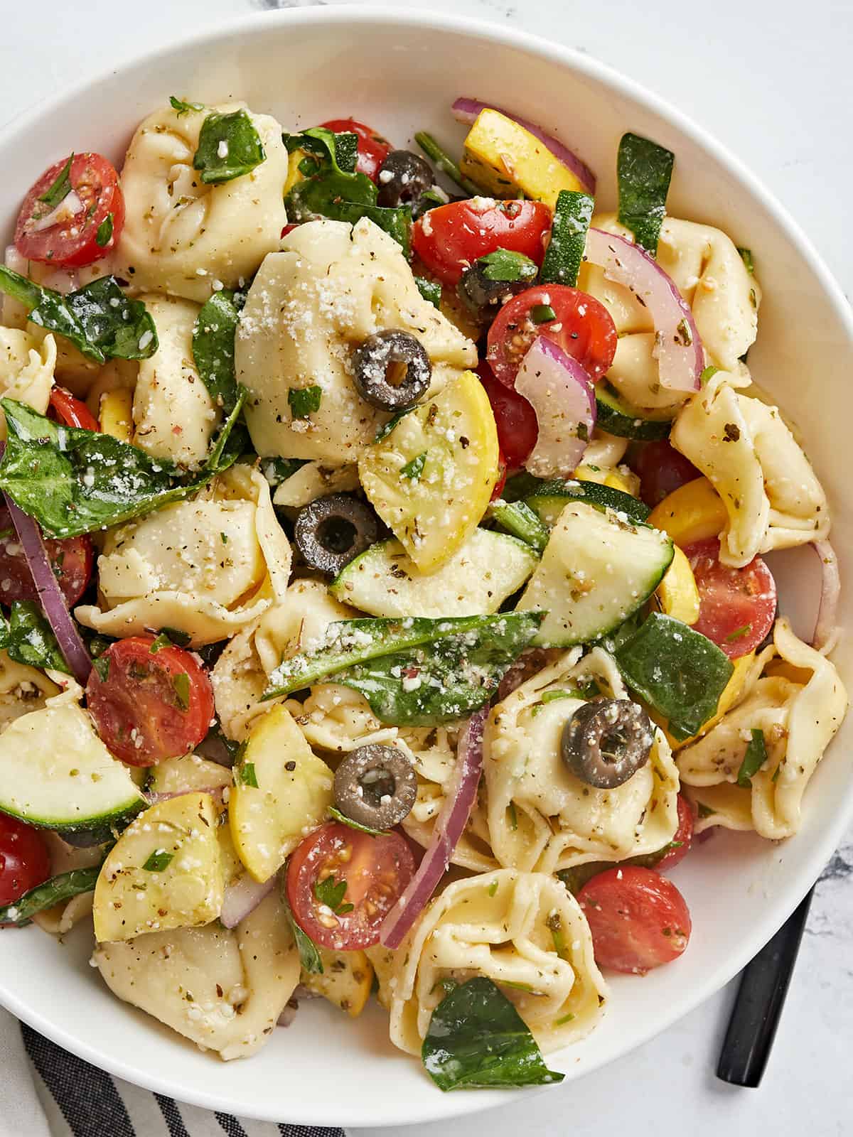 Overhead shot of tortellini salad in a white bowl.