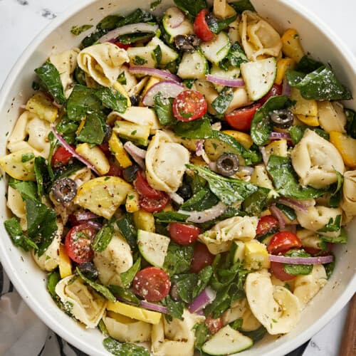 Overhead shot of tortellini salad in a white bowl.