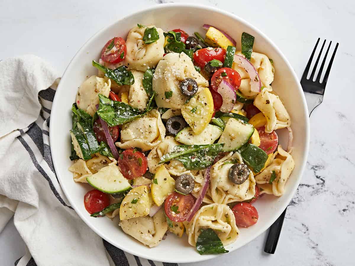 Overhead shot of tortellini salad in a white bowl.