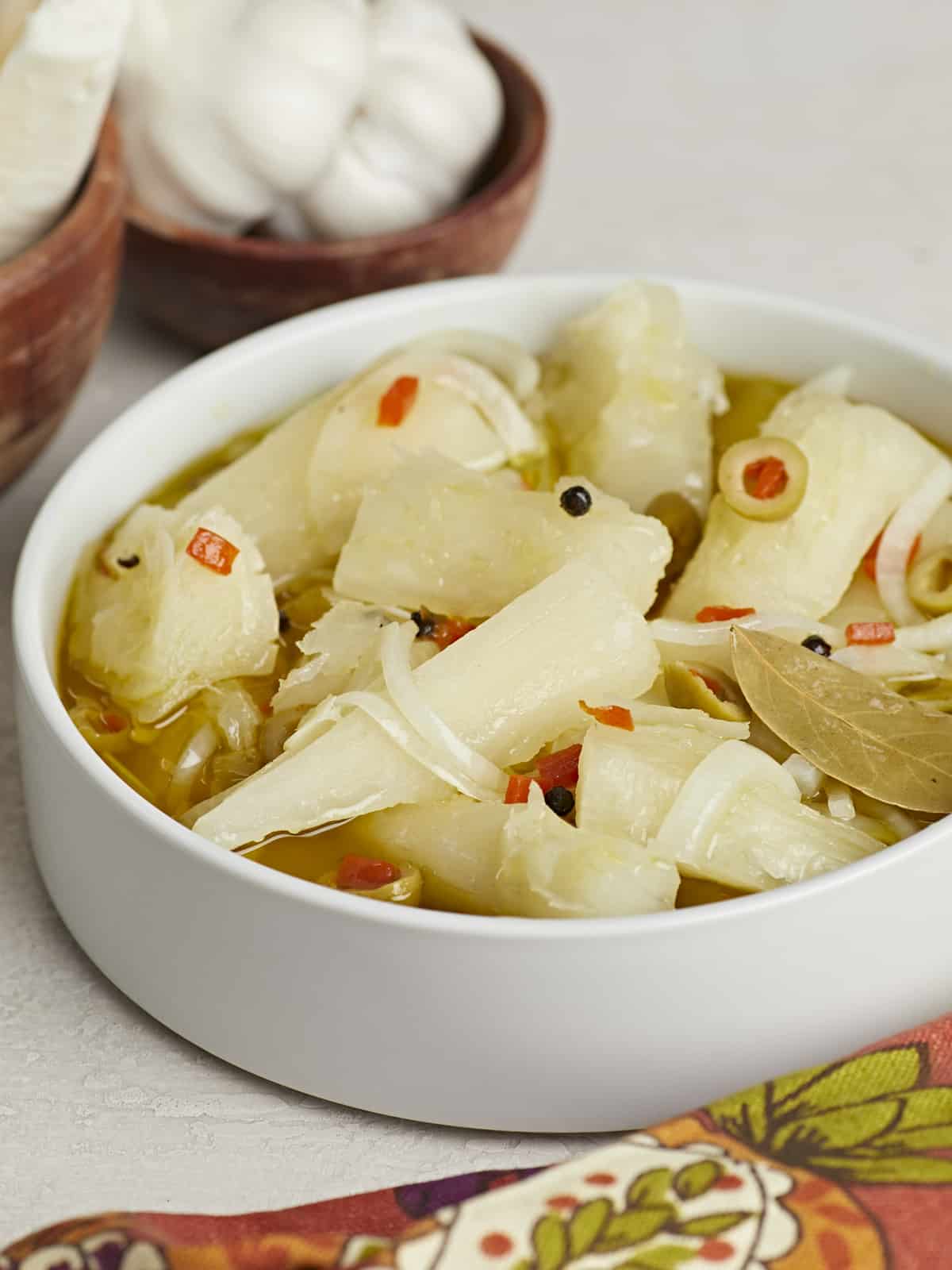 Side shot of Yuca En Escabeche in a white bowl.