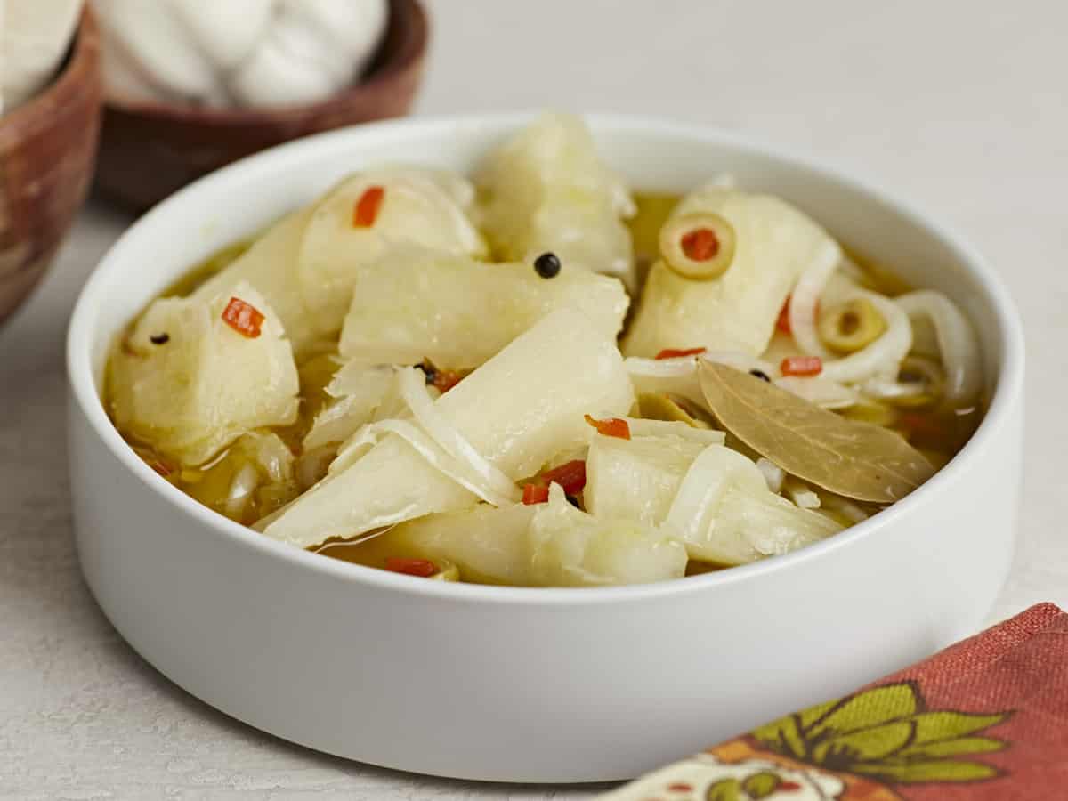 Side shot of Yuca En Escabeche in a white bowl.