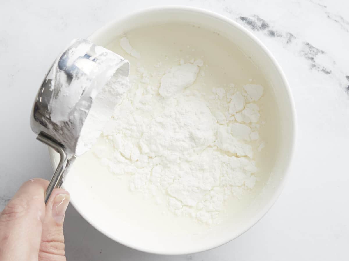 Overhead shot of cornstarch being added to milk.