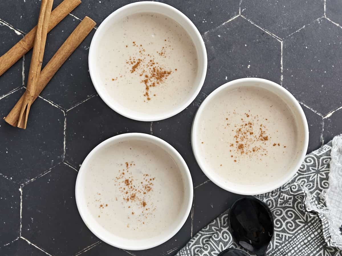 Overhead shot of three white bowls of Maizena with cinnamon sprinkled on top.