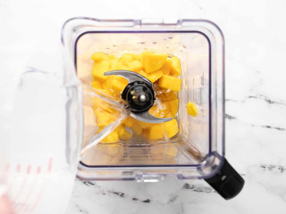 Overhead shot of mango and other ingredients in a blender.