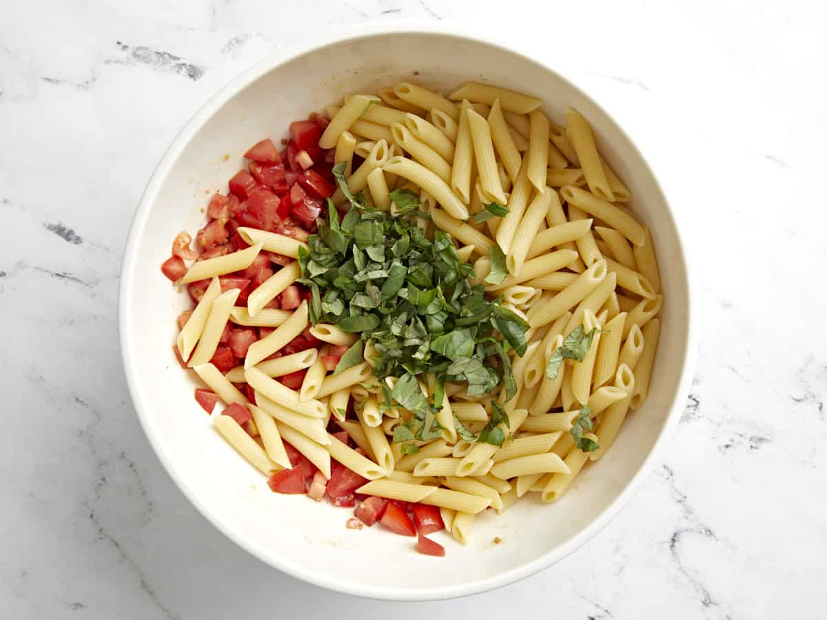 Pasta and basil added to the marinated tomatoes.