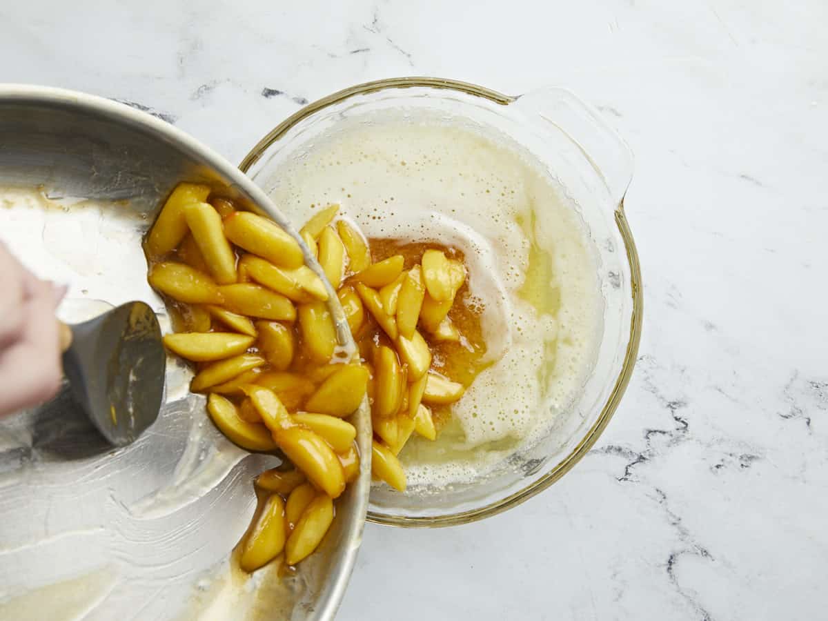 Overhead shot of cooked peaches being added to butter.