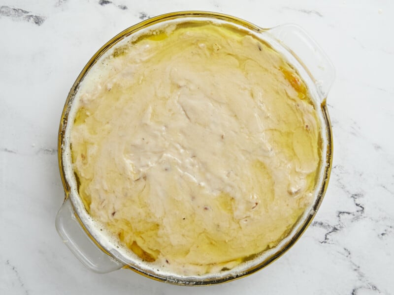 Overhead shot of raw peach cobbler in a glass pie plate.