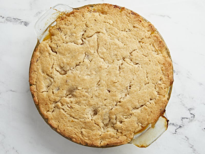 Overhead shot of baked peach cobbler in a glass pie plate.